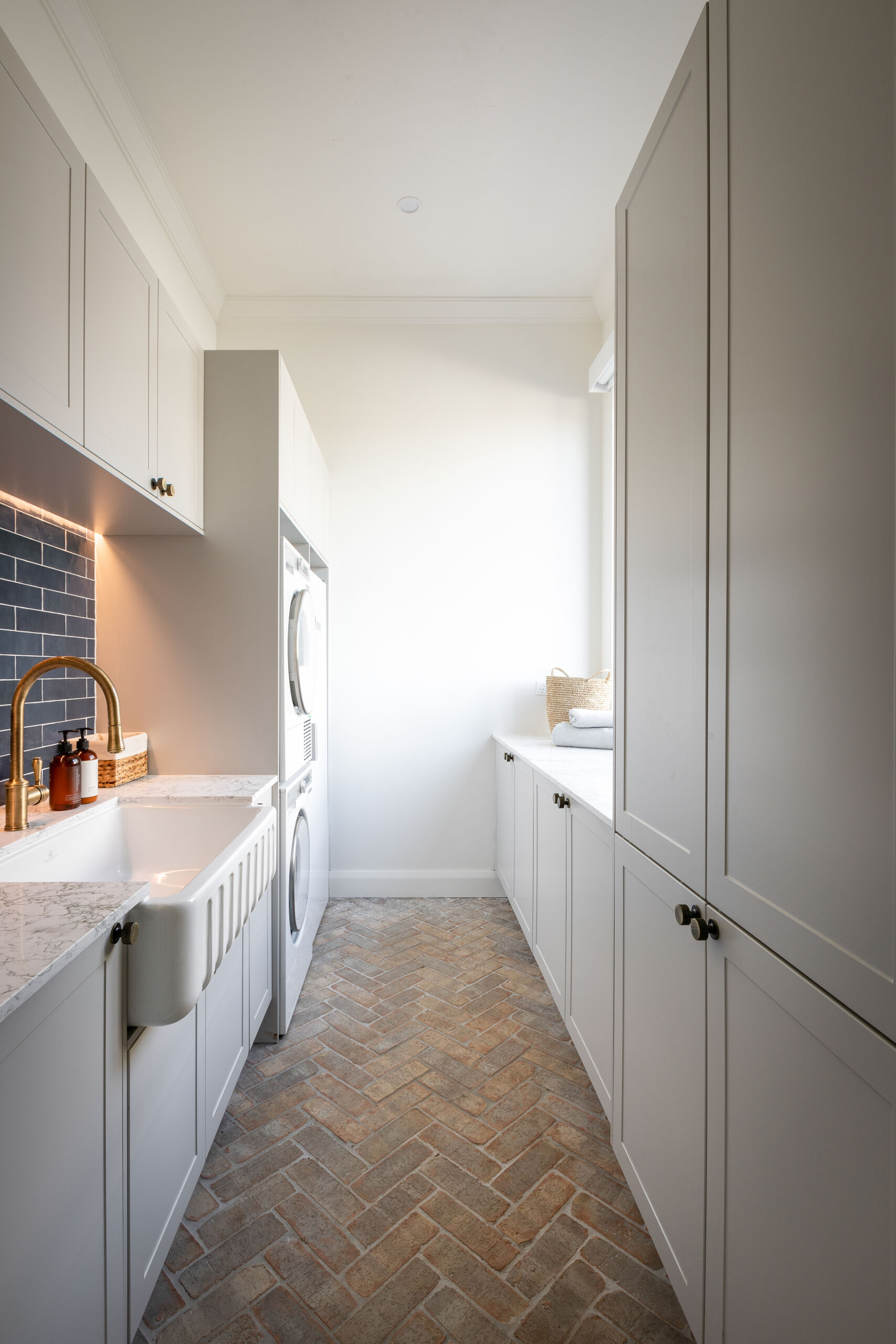 The Block's 2022 Tom and Sarah-Jane gallery-styled laundry layout offers abundant bench and internal storage space within a chic and calm laundry design.