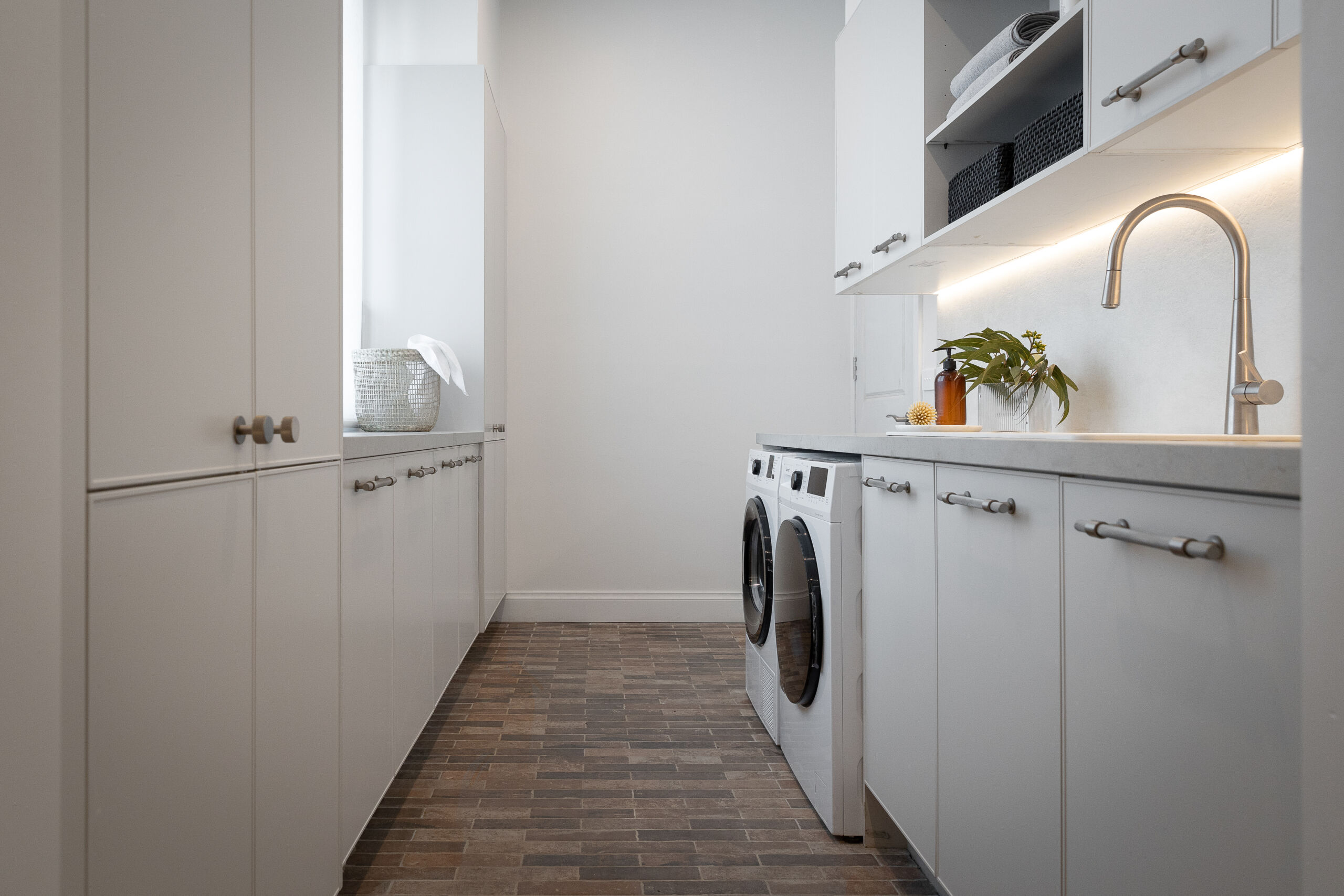 The Block 2022 Rachel and Ryan balance style and substance in their glamorous laundry room design. Fitted with a side by side washer and dryer combination and generous Ceasartone Primordia benchtop it provides ample storage space for work areas and easy organisation.