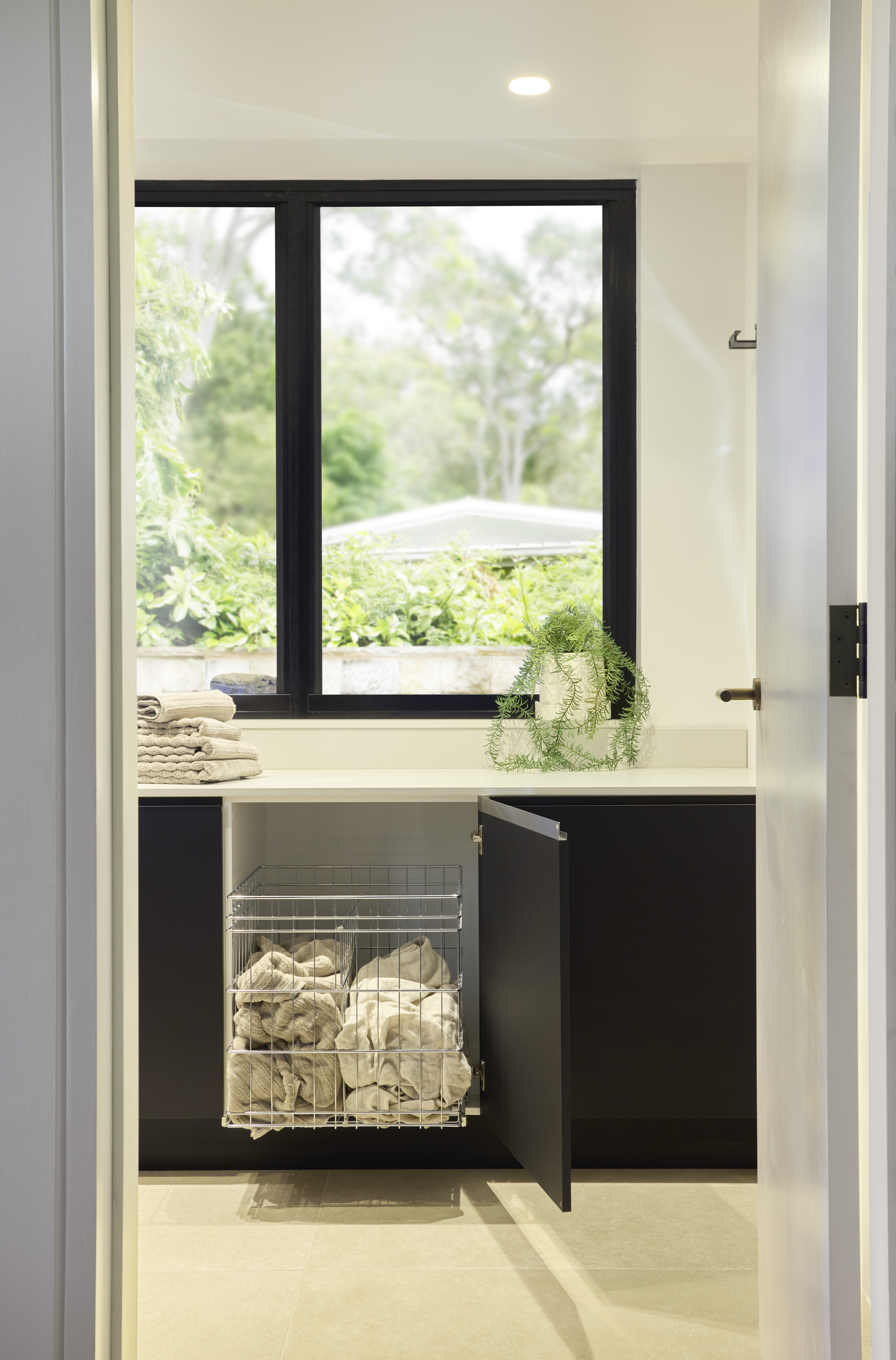 Avalon Laundry Portrait 3 Pull-out laundry hamper inside black cabinetry in a compact laundry