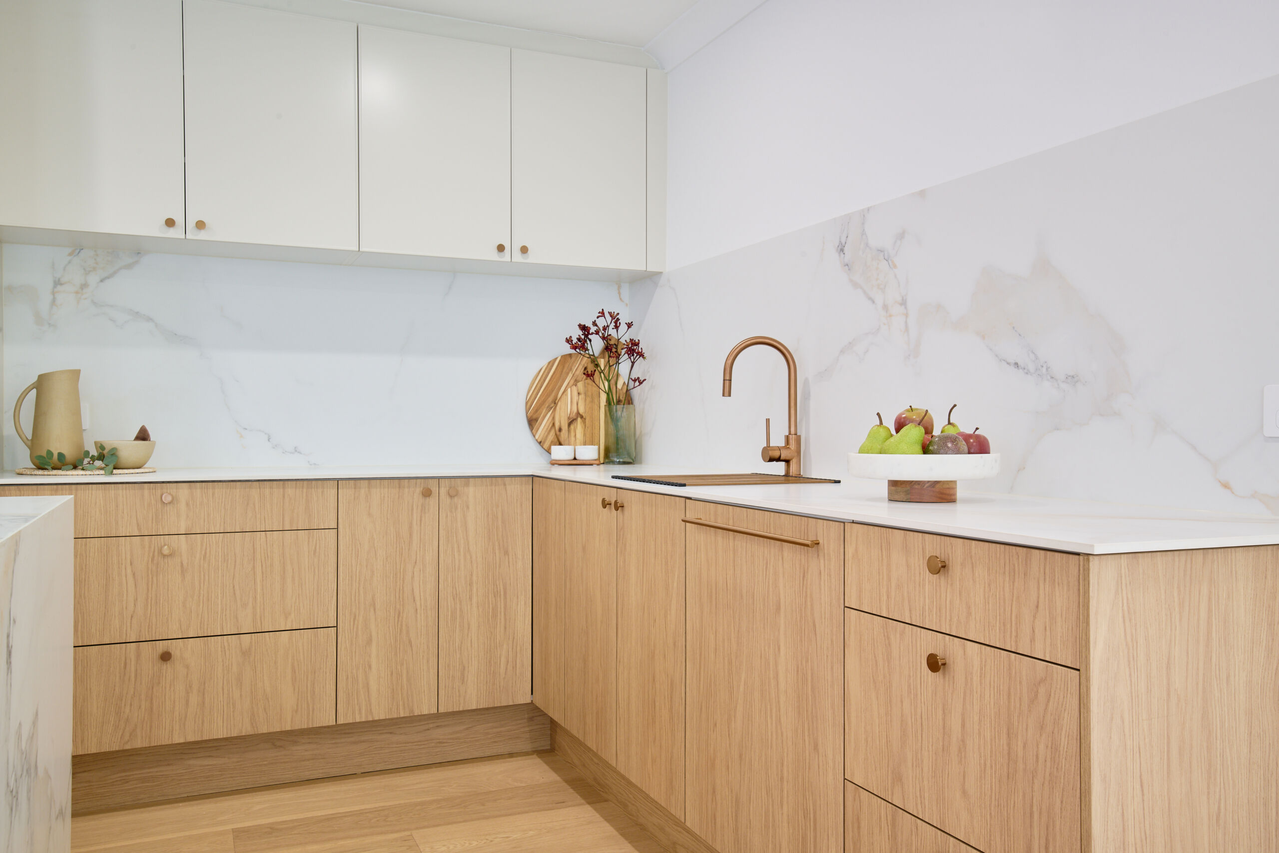 L-shaped kitchen layout with bronze hardware such as handles, tap and sink.