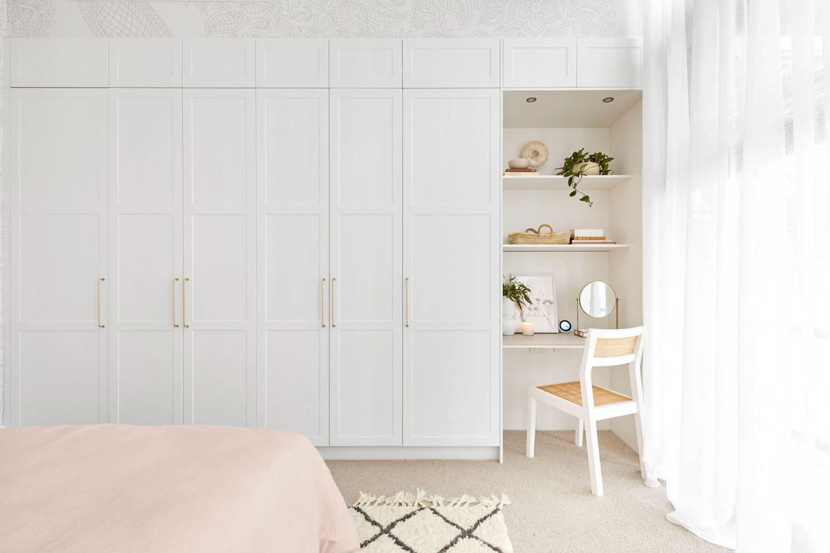 Built in wardrobe with white shaker doors, gold handles and desk area.