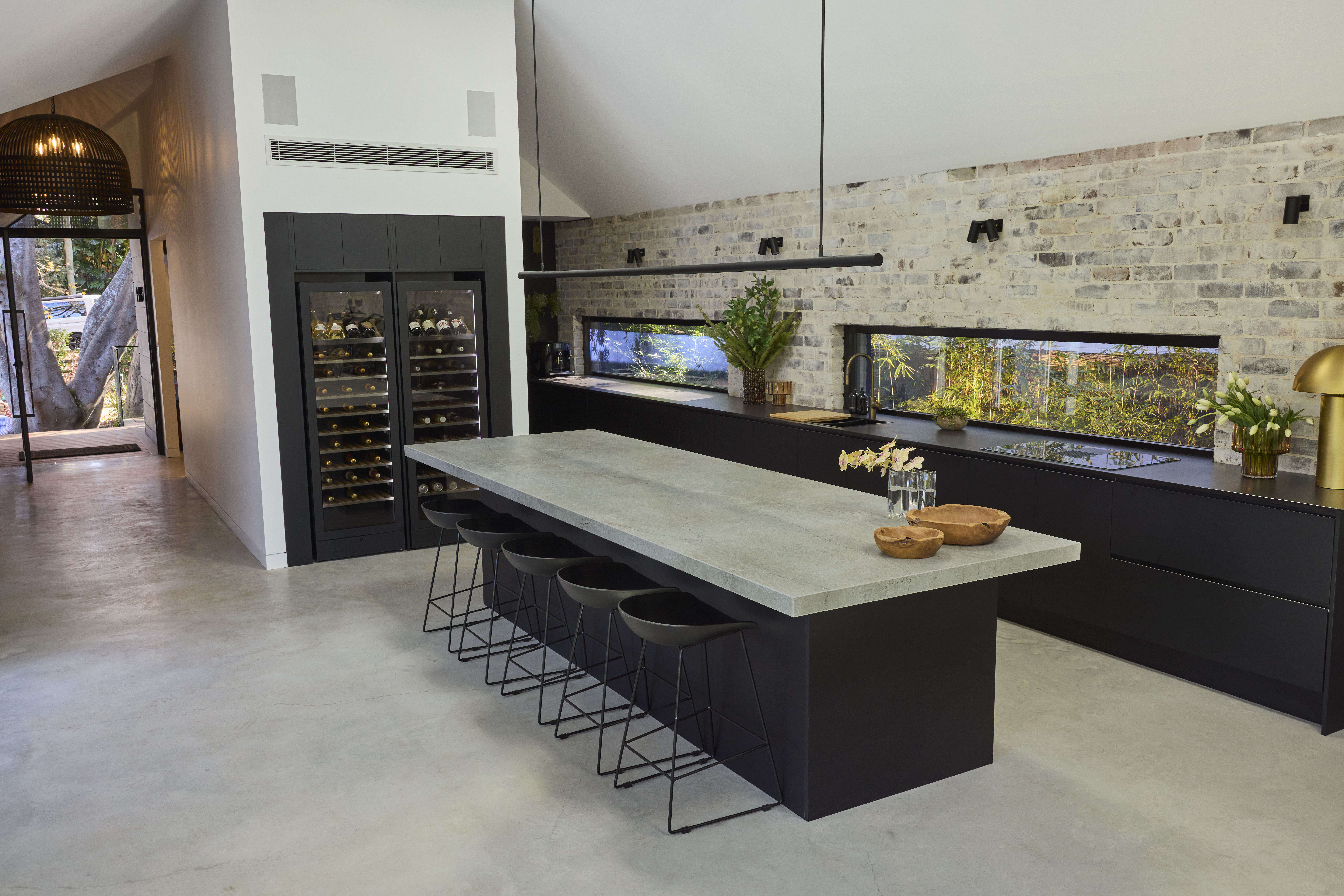 Modern black kitchen with concrete-look island bench and exposed brickwork