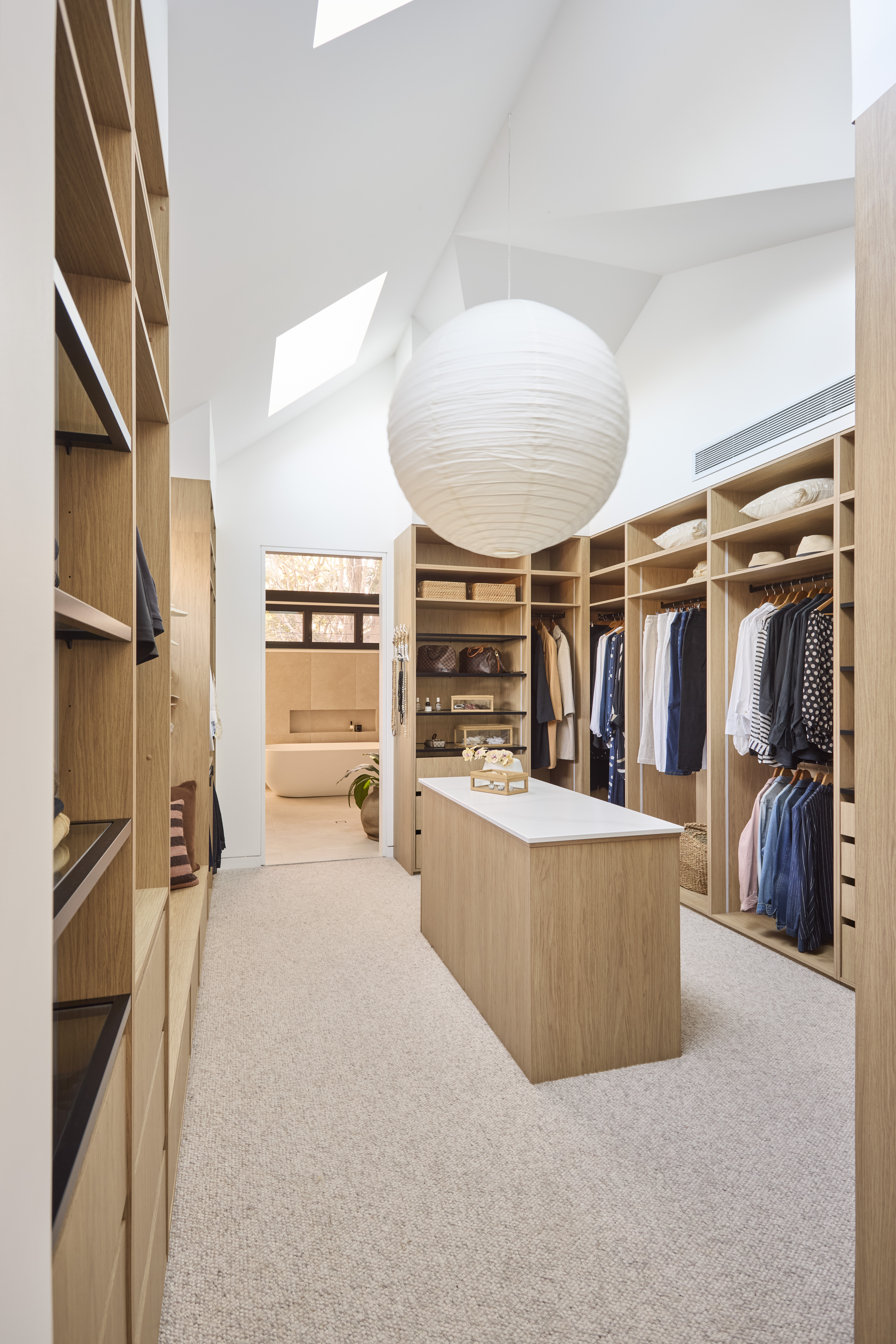 Walk in wardrobe with open timber shelves and an island bench