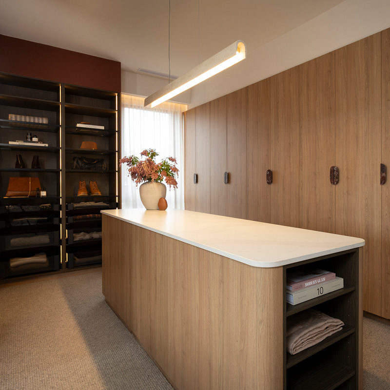 The Block 2025 – House 1 – Emma & Ben The Block 2025 - House 1 - Emma & Ben: Freedom Kitchens Block 25 reveal. A light timber walk-in wardrobe, curved island bench, open shelving, and dark cabinetry.