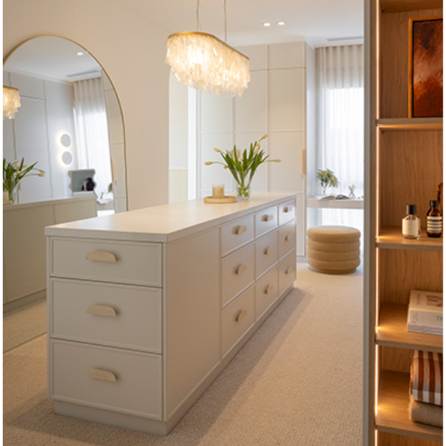 Large walk in wardrobe with island bench and timber look open shelving and makeup table