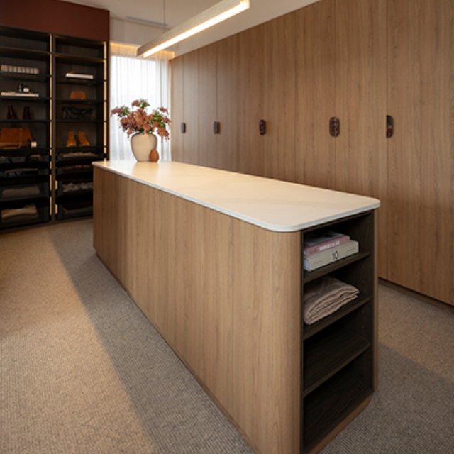 Walk in wardrobe with warm timber look cabinetry and a large island bench with open shelves