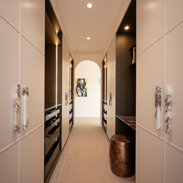 Walk in wardrobe with neutral white shaker wardrobe doors and stone look handles