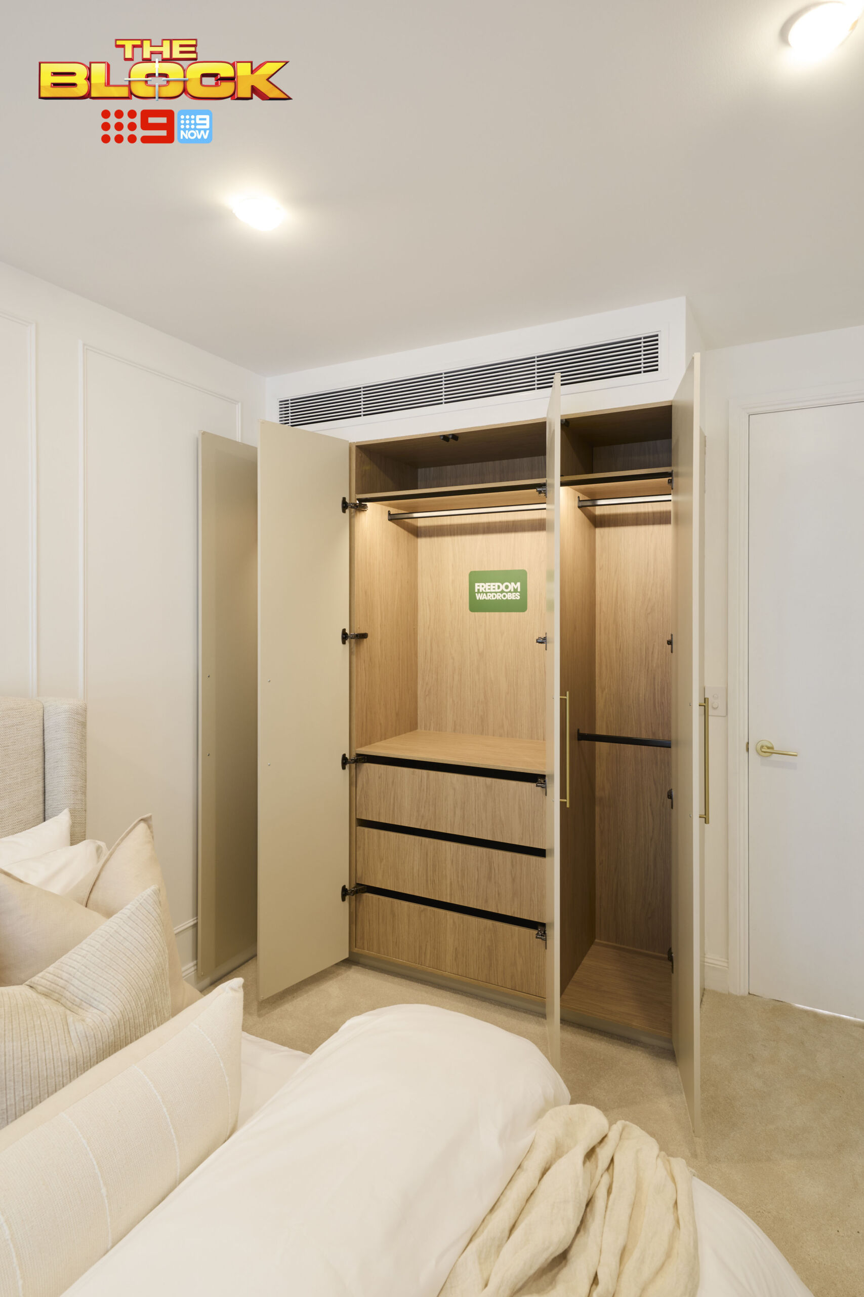 Built-in wardrobe with timber-look interiors featuring hanging rails, drawers, and open shelving for organised clothing storage.