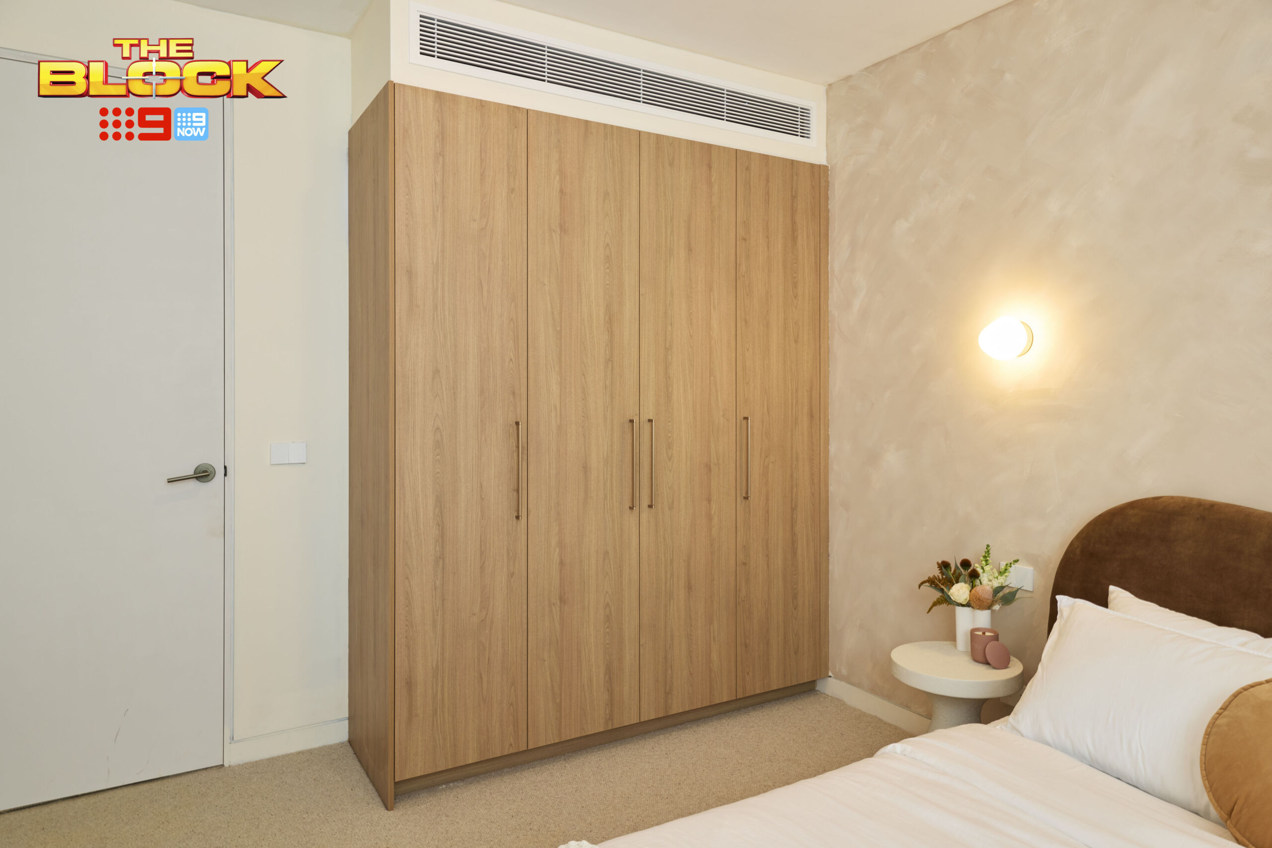 Built-in timber-look wardrobe with bronze handles in a modern guest room, complementing the contemporary interior design.
