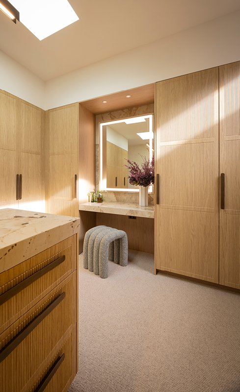 Dressing table, illuminated mirror and stone island in Adam and Jolene’s walk in wardrobe