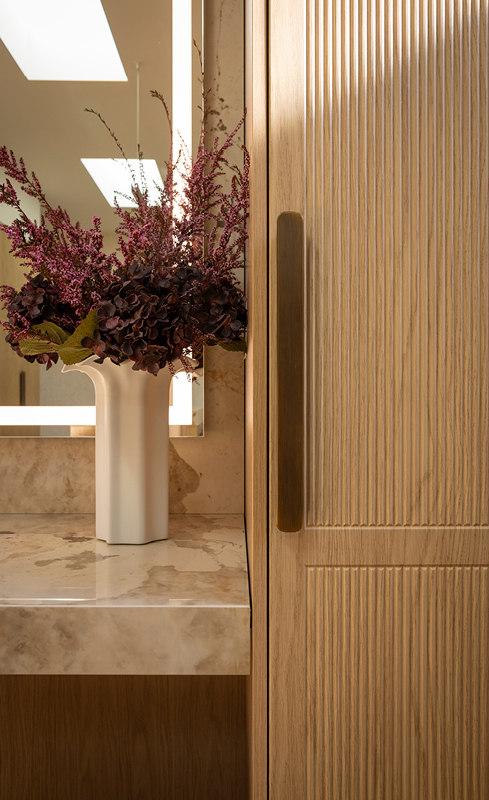 Fluted Nordic Oak wardrobe door with bronze handle beside stone dressing table