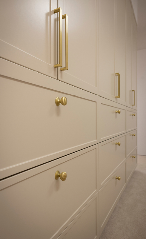 Brushed brass handles and knobs on greige shaker wardrobe cabinetry