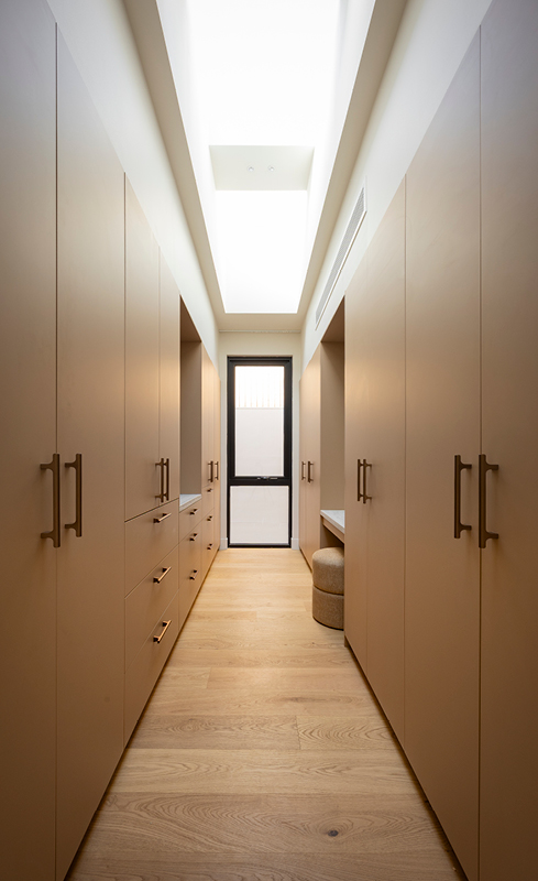 Courtney and Sev’s galley walk-in wardrobe with warm cabinetry and bronze handles