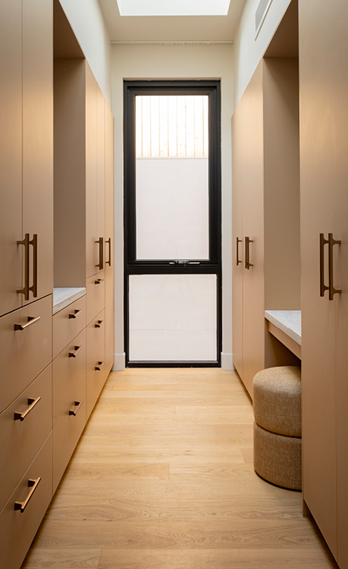 Galley walk-in wardrobe with open shelving, skylight and illuminated makeup mirror