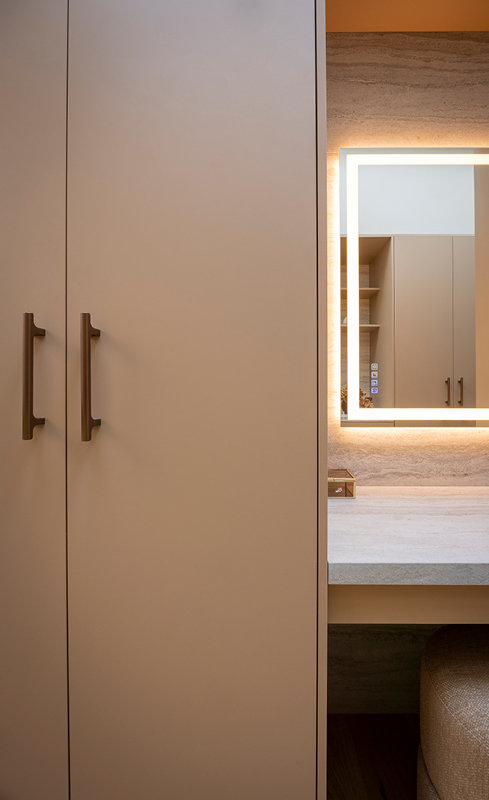 Wardrobe doors with bronze handles beside an illuminated Bluetooth mirror