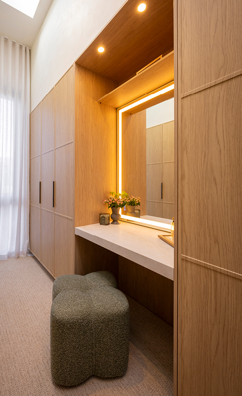 Coastal walk-in wardrobe with illuminated makeup mirror and Nordic Oak cabinetry