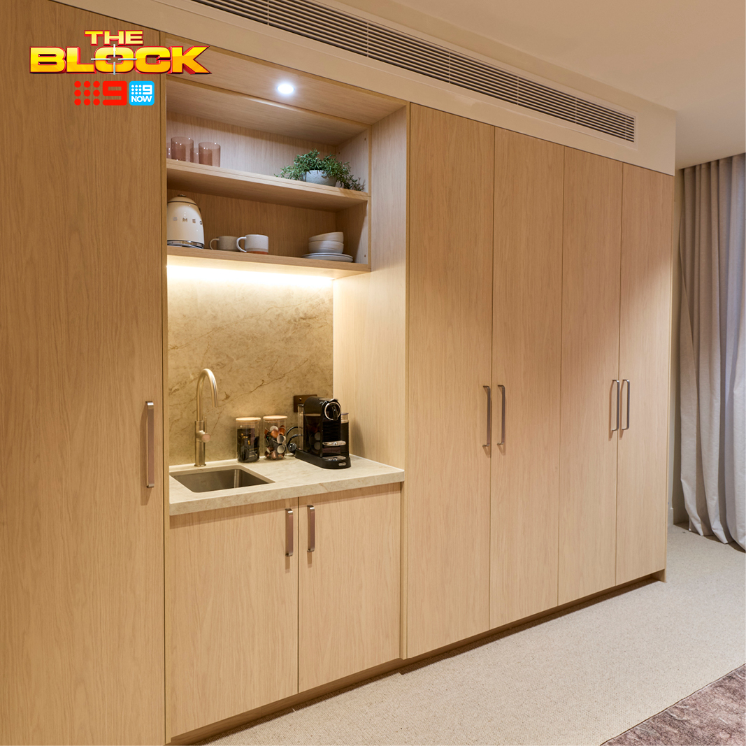 The Block 2026 – House 4 – Courtney and Sev Freedom Wardrobes built-in unit on The Block 2026, timber-toned cabinetry with an integrated bar nook featuring a sink, tapware and open display shelving with under-shelf lighting.