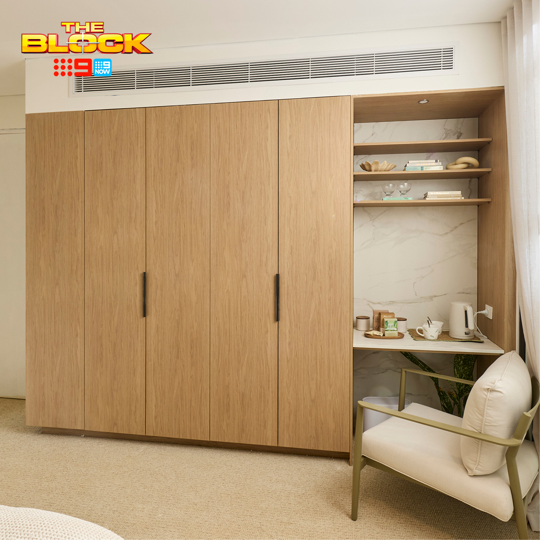 Freedom Wardrobes built-in wardrobe on The Block 2026, timber-toned cabinetry beside an open nook with marble-look splashback, desk and open shelving, next to an armchair.