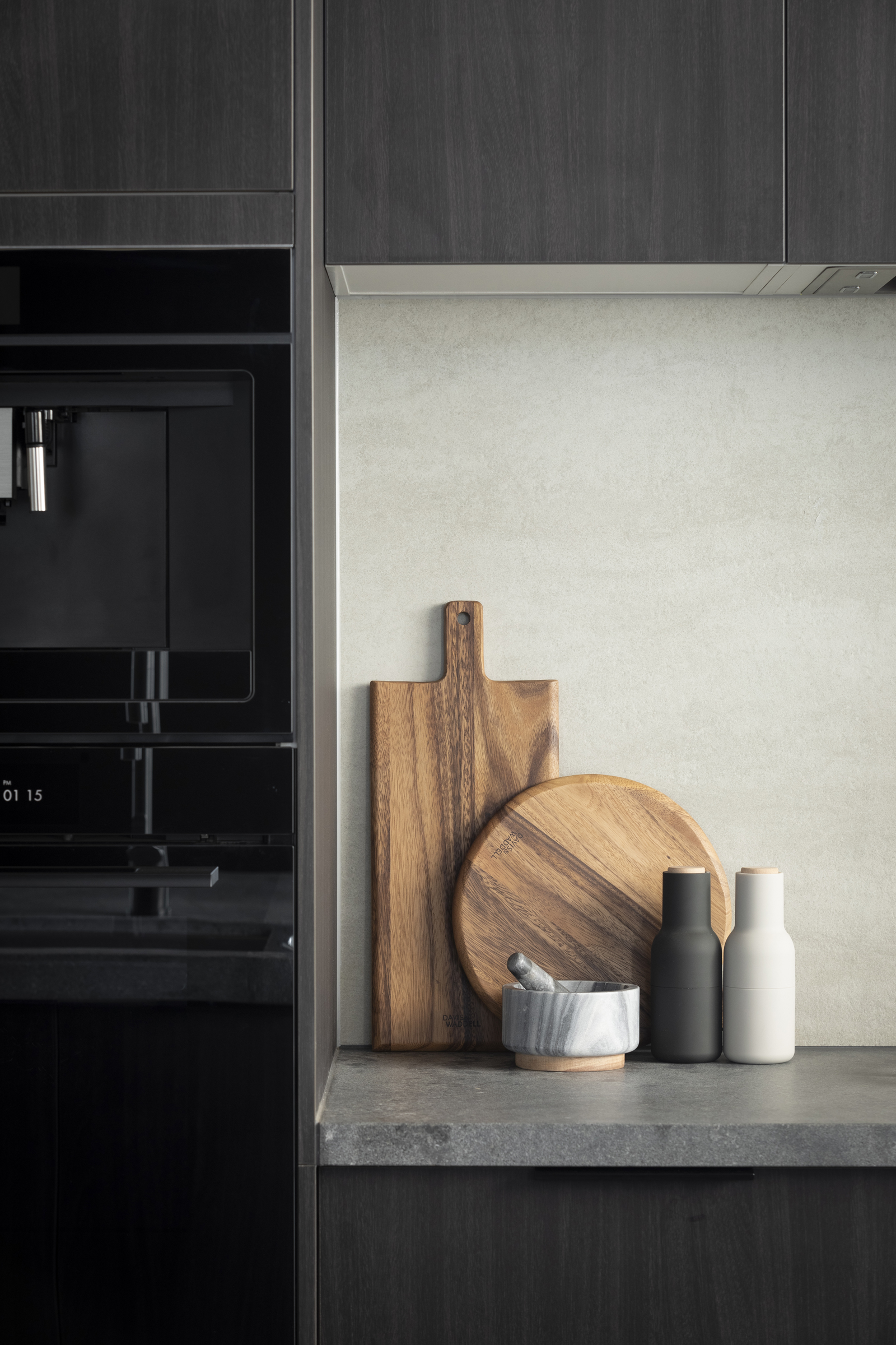 FM_MA117 Dark timber-look cabinetry and concrete-look benchtop styled with timber chopping boards