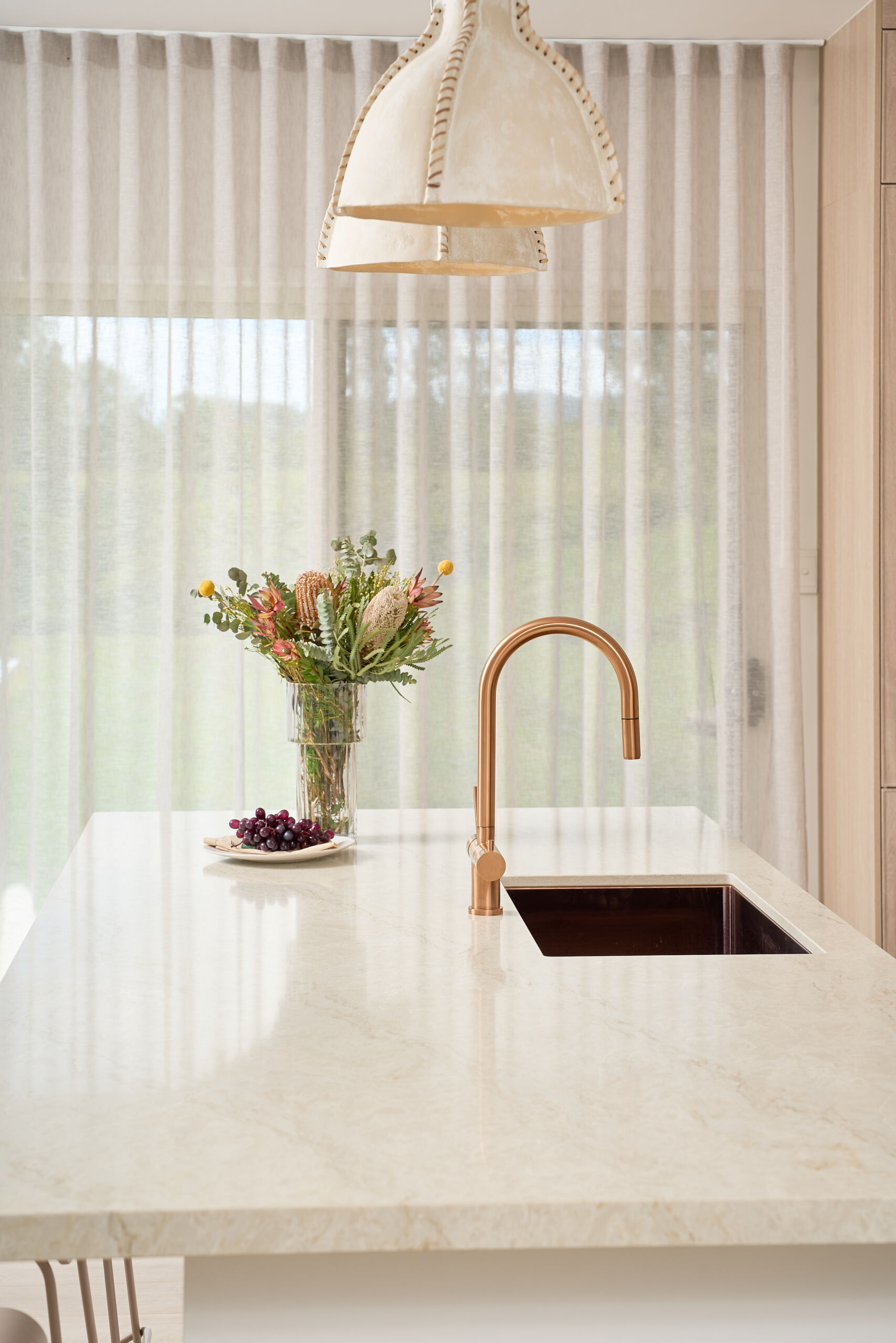 Brisbane Photographer Close up image of modern coastal kitchen focusing on the island bench and sink and tap and pendant lights