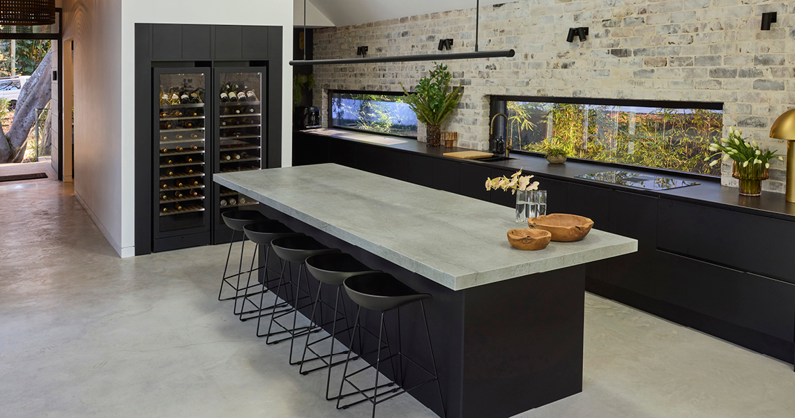 industrial-oct26-1 Industrial style kitchen with exposed brick wall, black cabinetry, stone island benchtop and built-in wine fridges