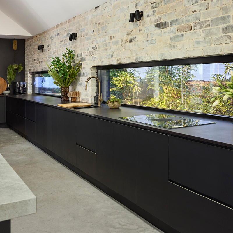 industrial-oct26-mob-3 Black kitchen cabinetry and benchtop against an exposed brick wall with a window splashback